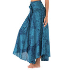 Jupe longue bohème bleue à motifs mandala, taille haute, avec ceinture nouée, portée par une femme pieds nus. Mode estivale élégante.