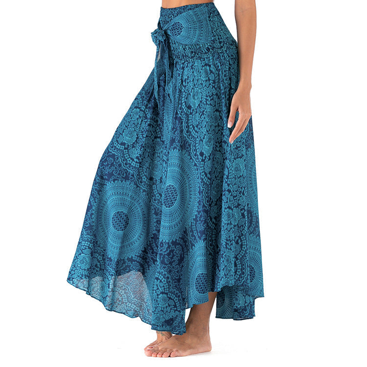 Jupe longue bohème bleue à motifs mandala, taille haute, avec ceinture nouée, portée par une femme pieds nus. Mode estivale élégante.
