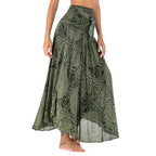 Jupe longue verte à motifs floraux, style bohème, portée par une femme pieds nus. Mode féminine, tendance été, élégance décontractée.