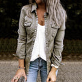 Femme portant une chemise kaki, un haut blanc et un jean bleu, tenant une boisson. Mode décontractée, style automne, accessoires bracelets.