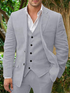 Homme en costume gris clair élégant, chemise blanche, posant en extérieur. Mode masculine, style formel, tendance vestimentaire.