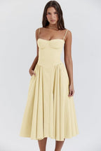Robe jaune élégante à bretelles fines, coupe évasée, portée par une femme. Mode féminine, tenue estivale chic, style décontracté.