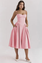 Robe rose élégante avec bretelles fines, jupe évasée, portée par une femme. Mode féminine, tenue chic, style classique.