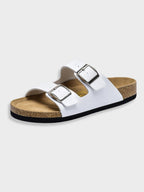 Sandale blanche à deux brides avec boucles argentées, semelle en liège et base noire. Chaussure confortable et tendance pour l'été.