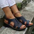 Sandales noires en cuir pour femme avec talon compensé, portées avec un jean blanc déchiré. Chaussures d'été élégantes et confortables.