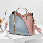 Sac à main en cuir bicolore bleu et rose avec poignée dorée, pendentif cœur, design élégant. Accessoire mode femme tendance et chic.