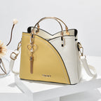 Sac à main bicolore jaune et blanc avec bandoulière, poignée dorée et pendentif cœur. Design élégant et moderne, idéal pour la mode féminine.