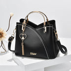 Sac à main noir élégant avec poignées dorées, bandoulière amovible, pendentif cœur et coutures blanches. Accessoire mode femme chic et moderne.
